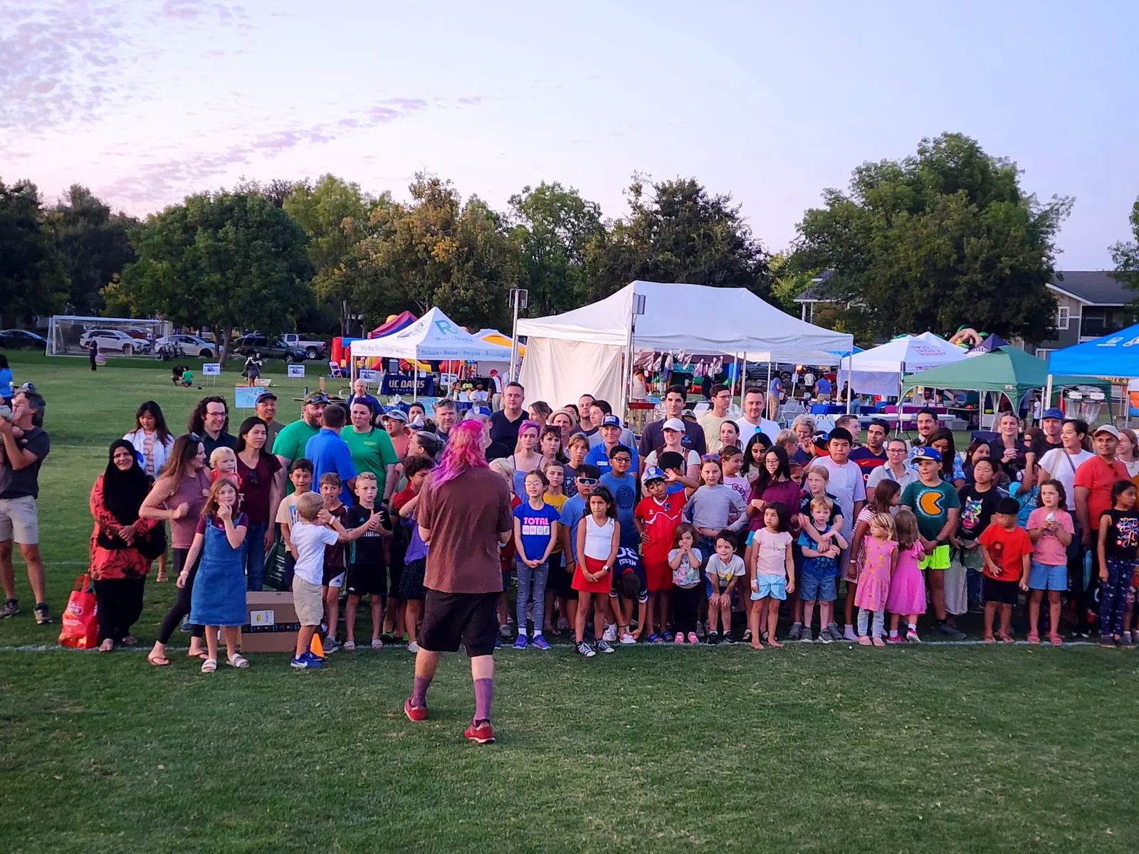 Festival crowd gathers among vendor tents in golden evening light